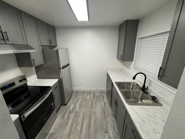 Second view of the remodeled kitchen showing new cabinets, counters, and flooring
