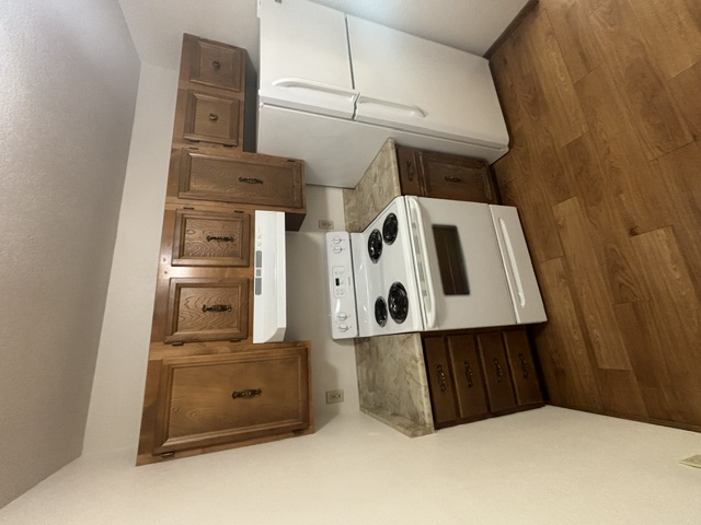 Dated apartment kitchen with worn brown cabinets and old appliances before remodel