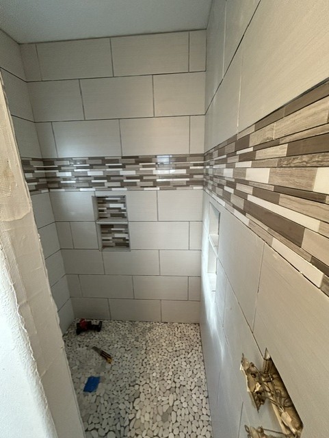 Newly tiled walk-in shower with accent tile band and pebble floor