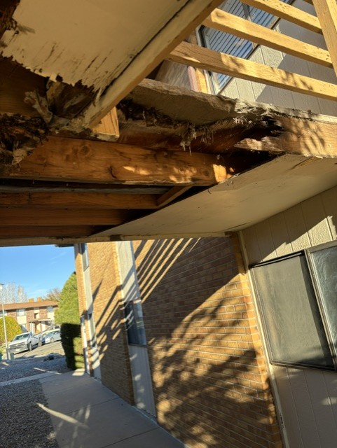 Rotted and damaged wood framing under an exterior apartment staircase before repair