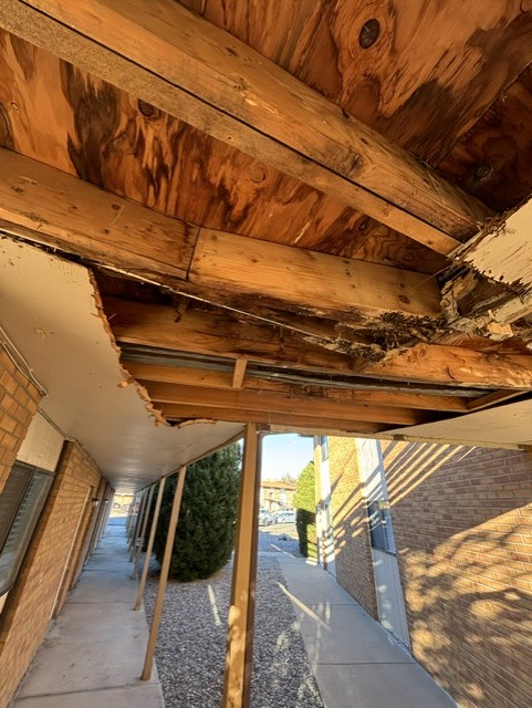 Close view of rot and structural damage in walkway overhang framing before repair